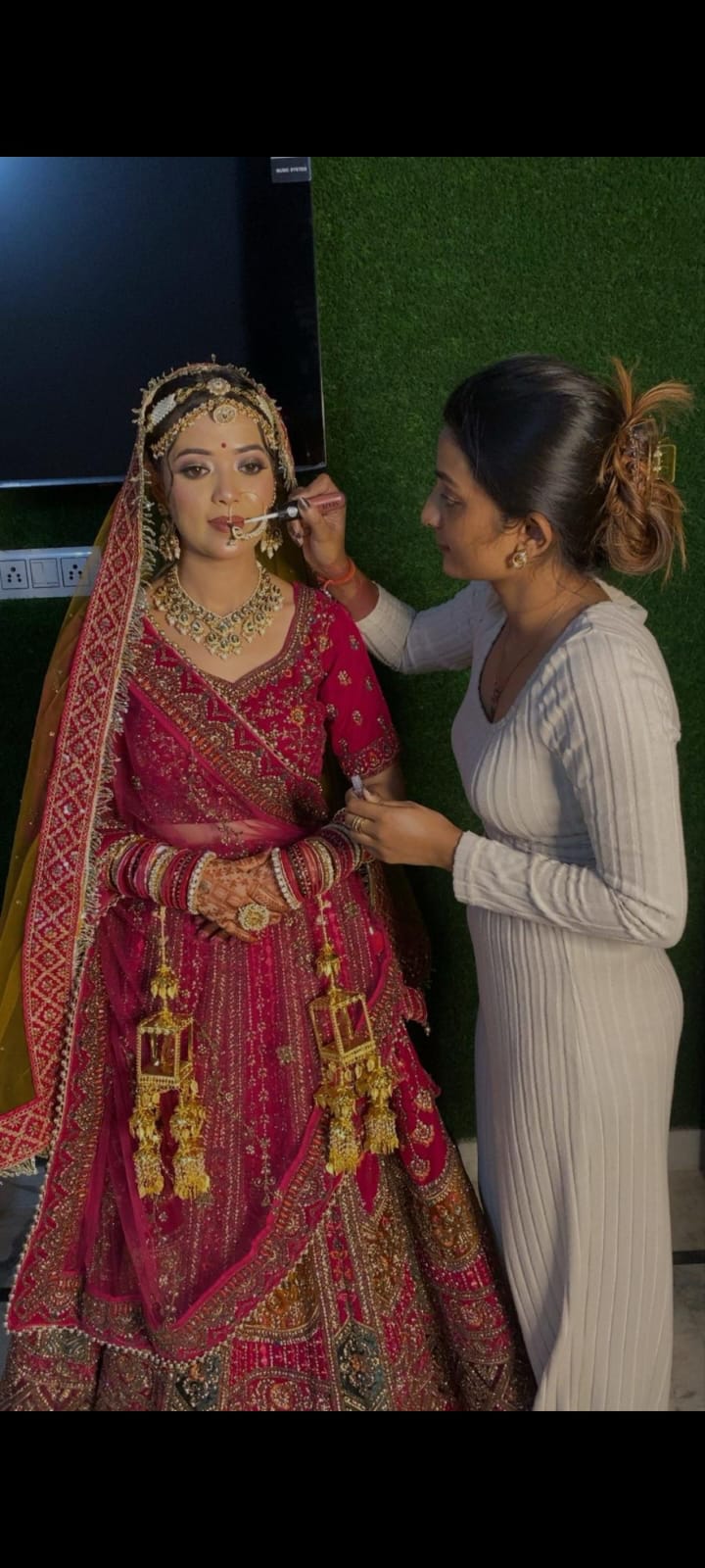 Final lipstick touches for a bride in pink lehenga